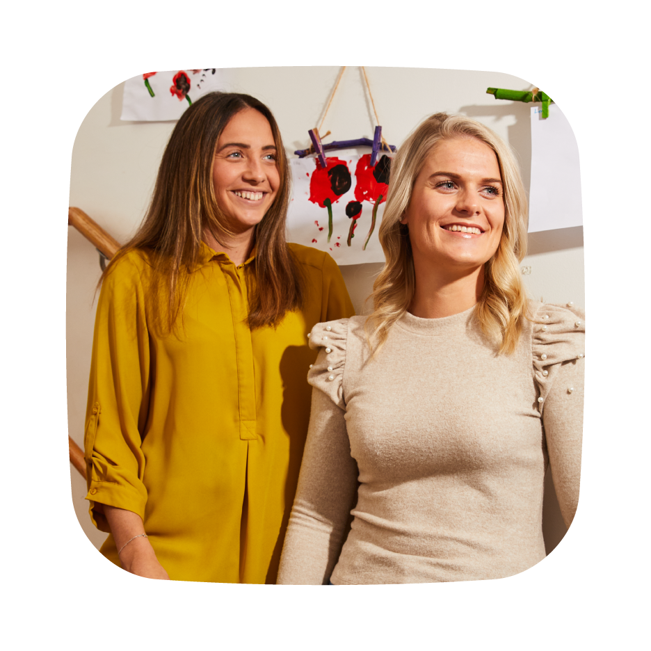 A photo of two women standing and smiling, appearing relaxed and engaged