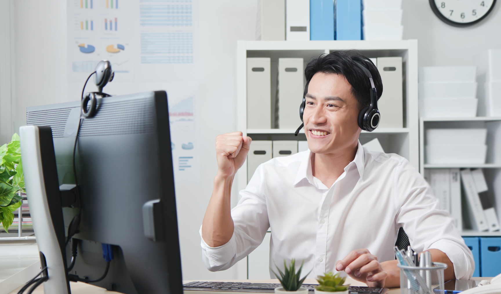 Employee making a yes sign with a fist towards the computer