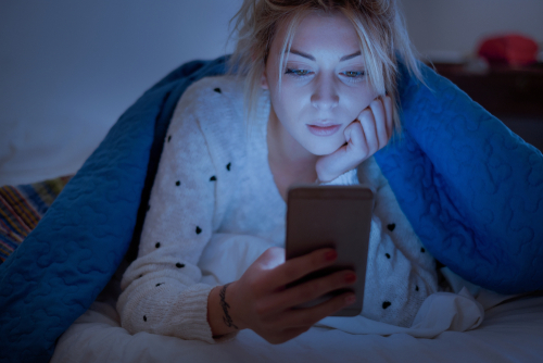 Woman looking at smartphone in bed