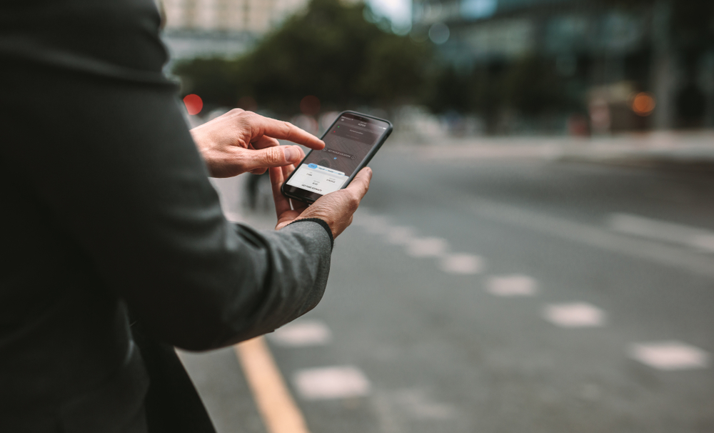 man holding smartphone finding rideshare