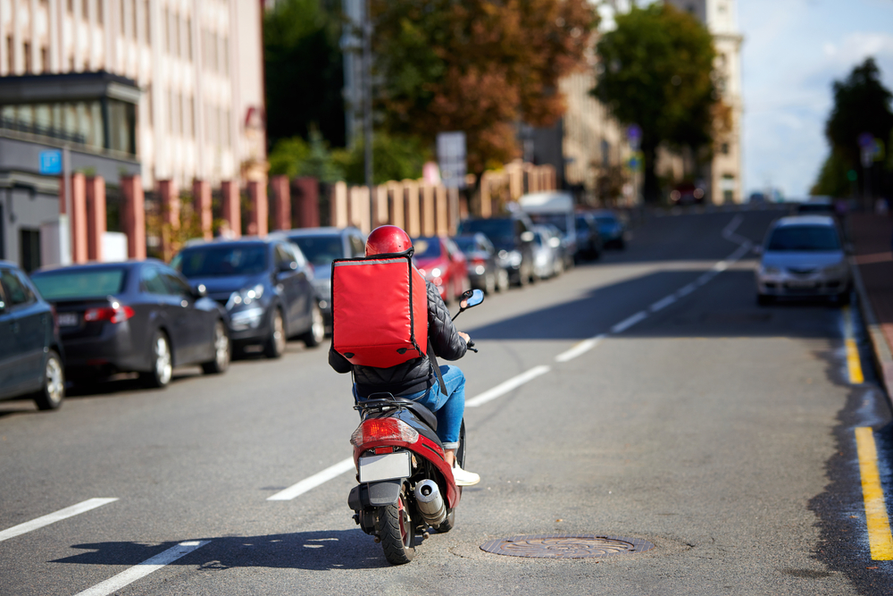 food courier on scooter with a red backpack