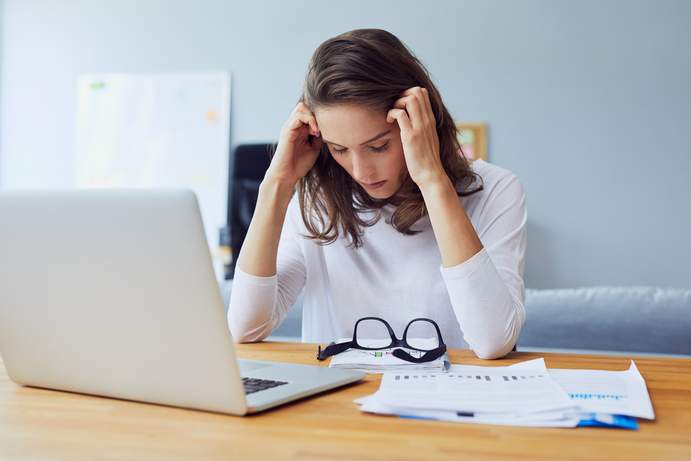 Woman sitting at work desk looking distressed