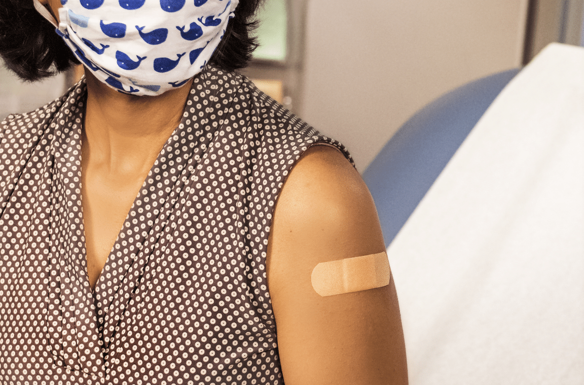 Woman wearing mask receiving vaccine
