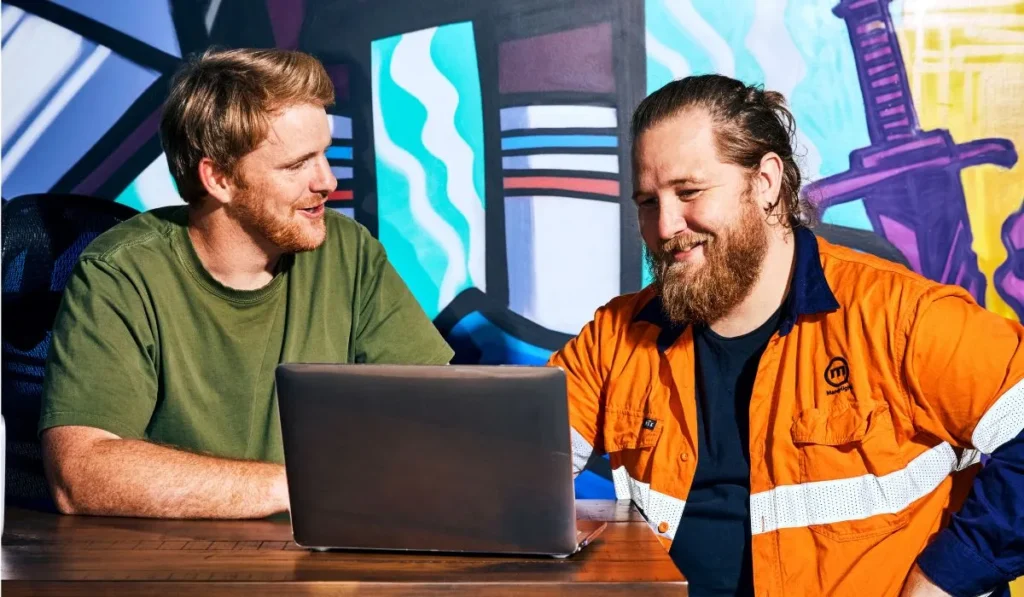 Two men discussing work on their laptop