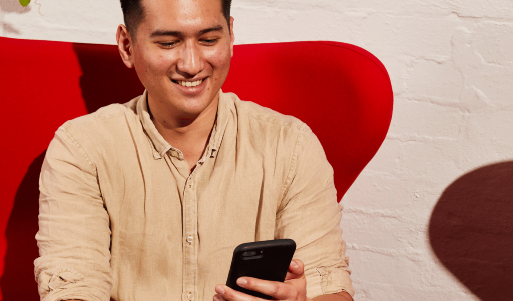 man smiling on his phone upon receiving a job offer email