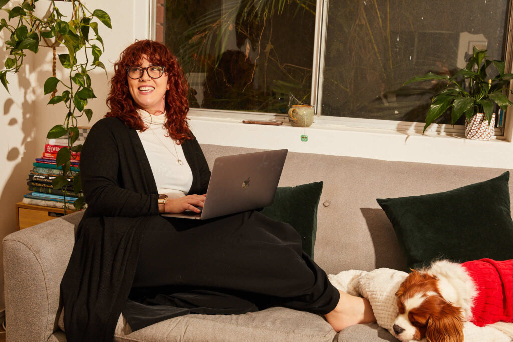 woman sending emails on the couch, a puppy by her side