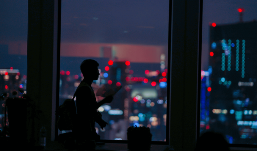 Silhouette of man walking in front of night cityscape