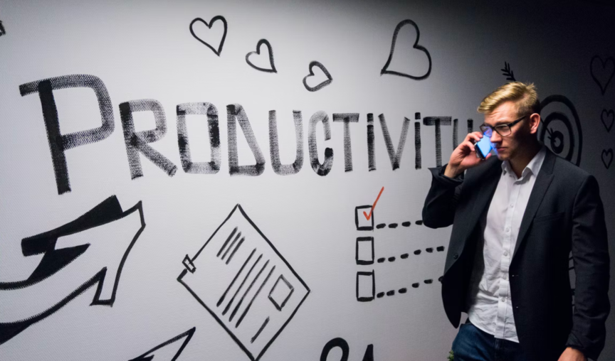 man on phone walking beside a wall that says productivity