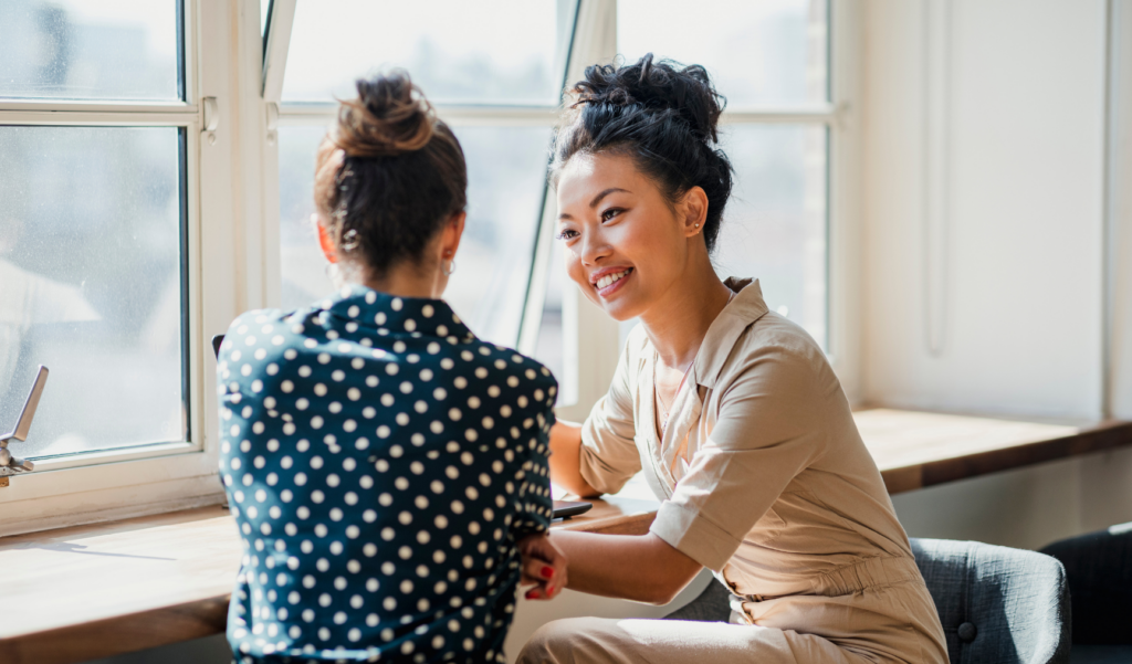 Manager and employee having a one-on-one performance review meeting by the window.