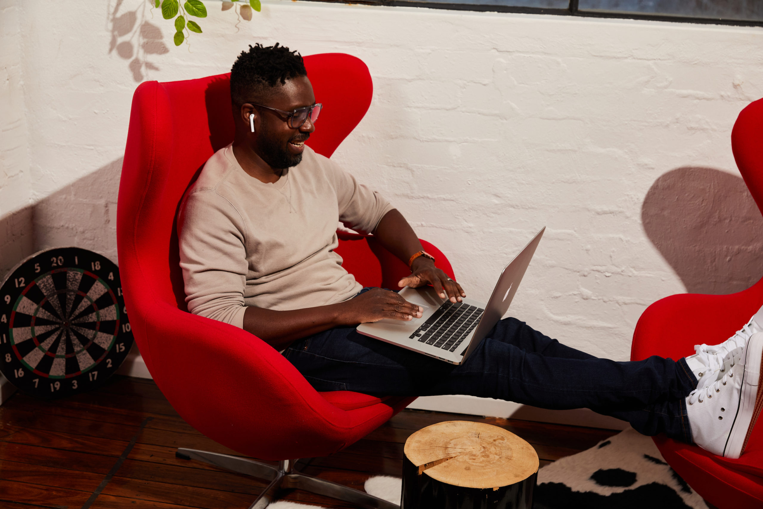 employee sitting in an armchair smiling while using his laptop