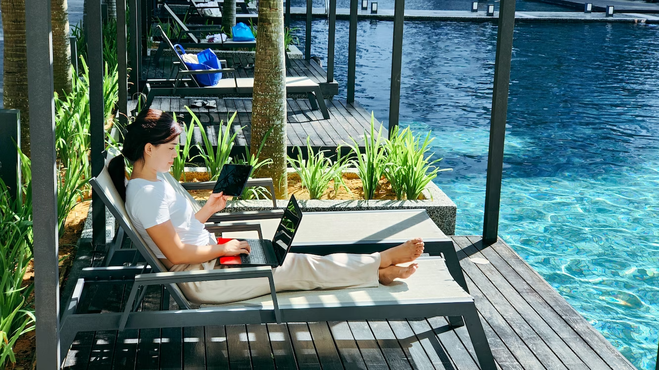 woman sitting on a deck chair by the pool remote working