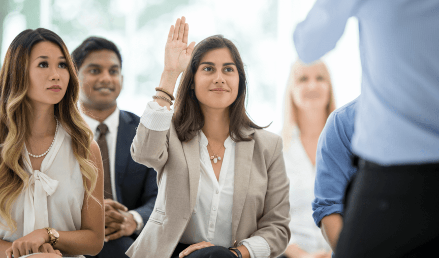 workers attending an in-person course with woman raising her hand