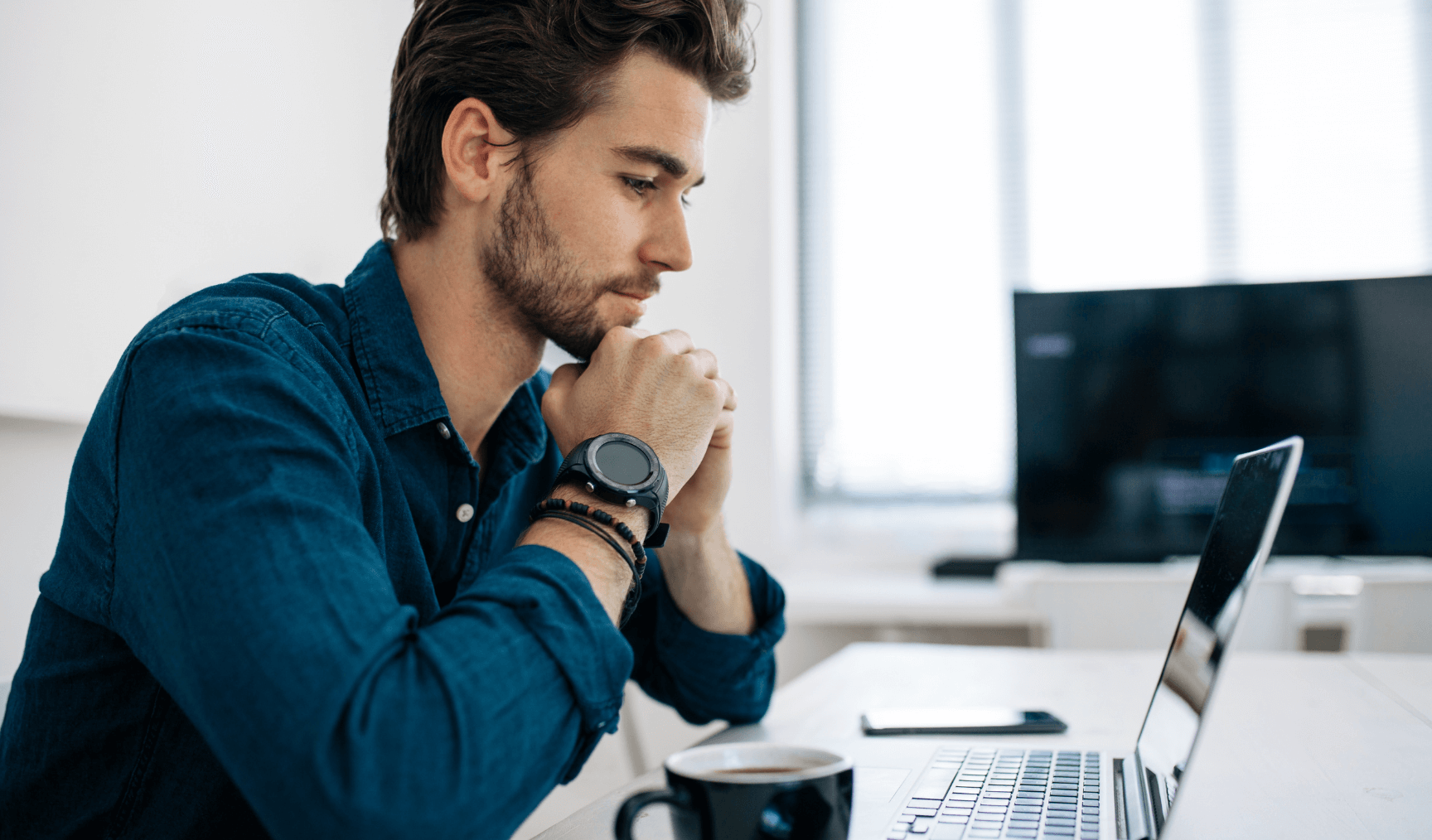 man sitting in front of his laptop with hands together