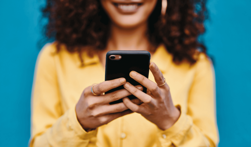 This is an image of a woman holding a mobile phone and smiling.