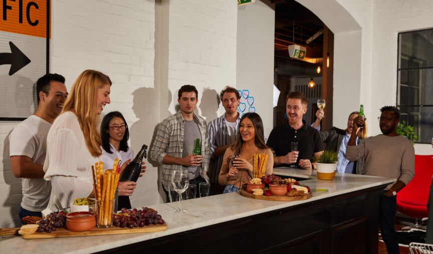 Group of employees are a company celebrating at a shared space in an office, wine and cheese is available