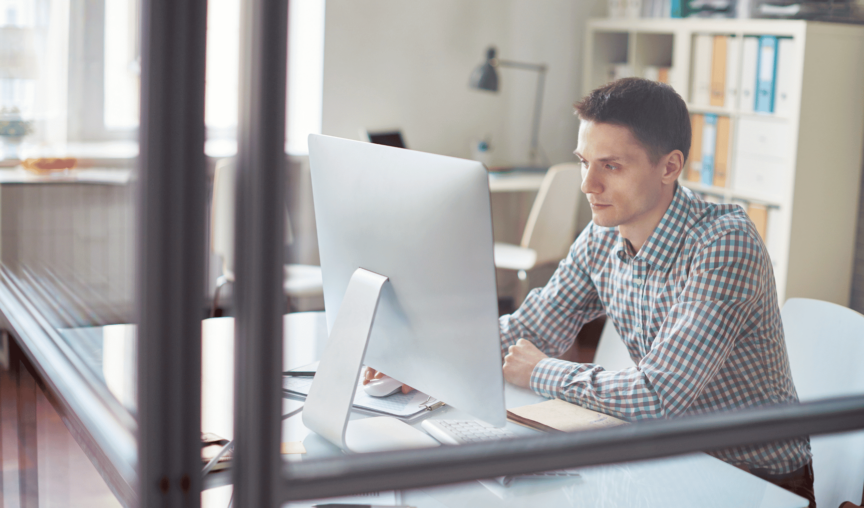 Man working at his computer in a closed office.