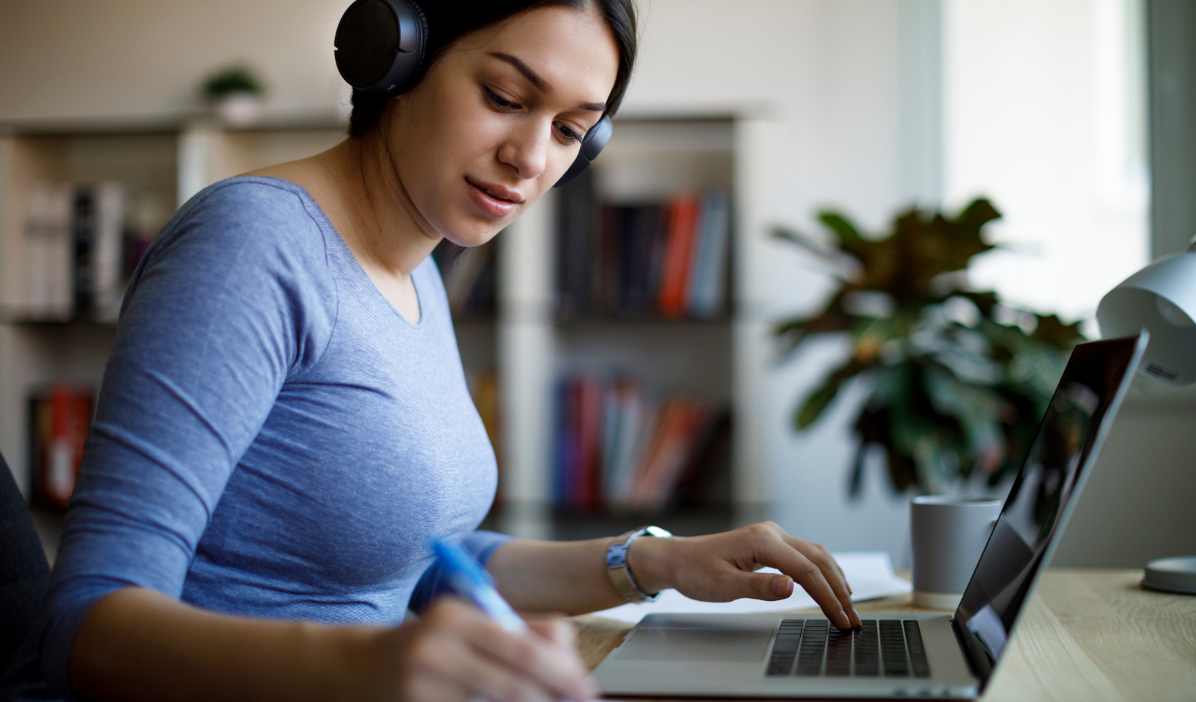 Woman writing down notes while working from home