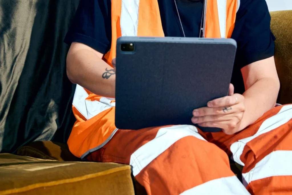 Close-up of a contractor in high-visibility gear using a tablet for work documentation.