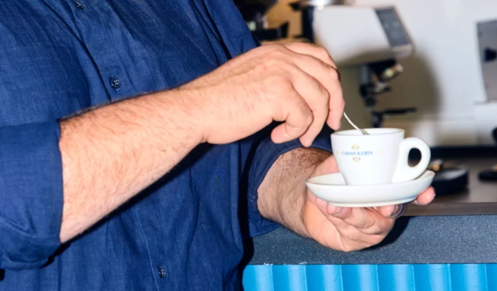 A close-up of a person stirring coffee on a work break, representing the need to review the employee's regular work pattern for eligibility for casual conversion.