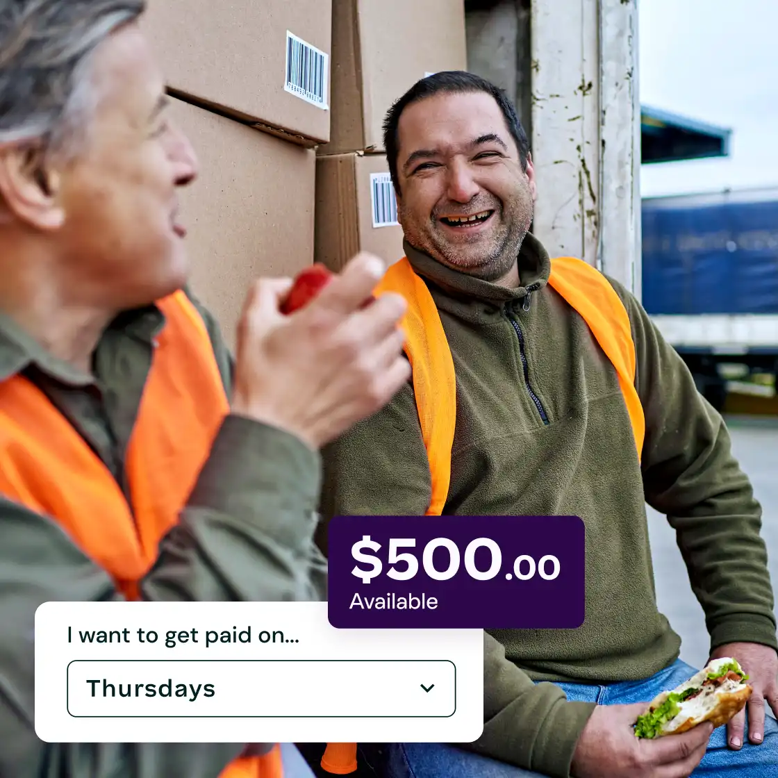 Two workers in orange vests share a light moment while eating, sitting by stacked boxes. Overlaid text shows '$500.00 Available' and payday set to 'Thursdays'.