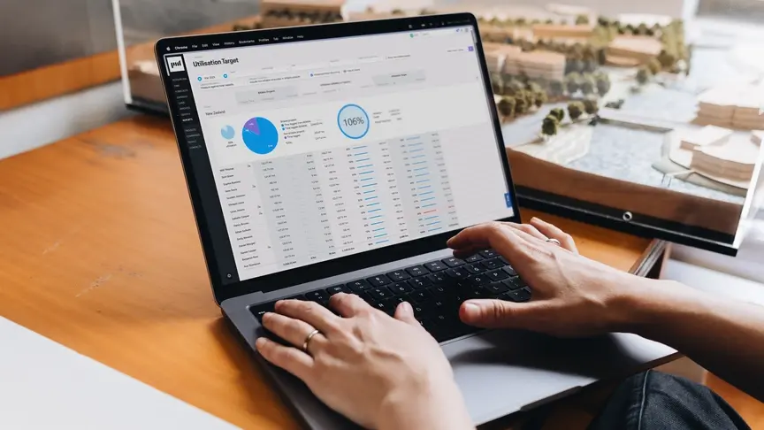 “Person working on a laptop displaying a utilization target dashboard with charts and data tables.”