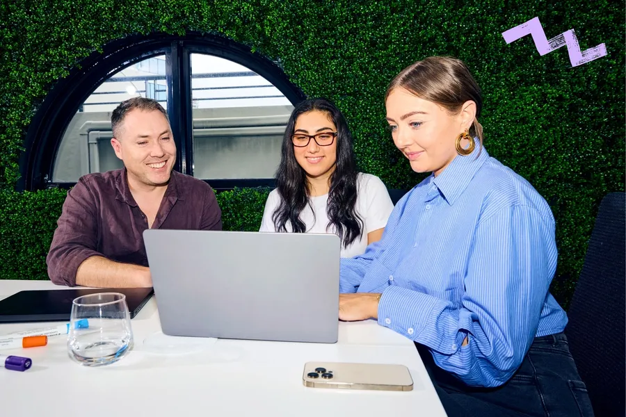 Colleagues smiling in front of a laptop.