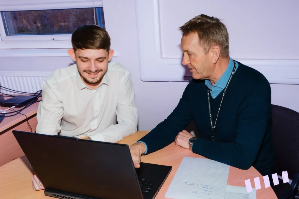 Two men discussing while working on a laptop