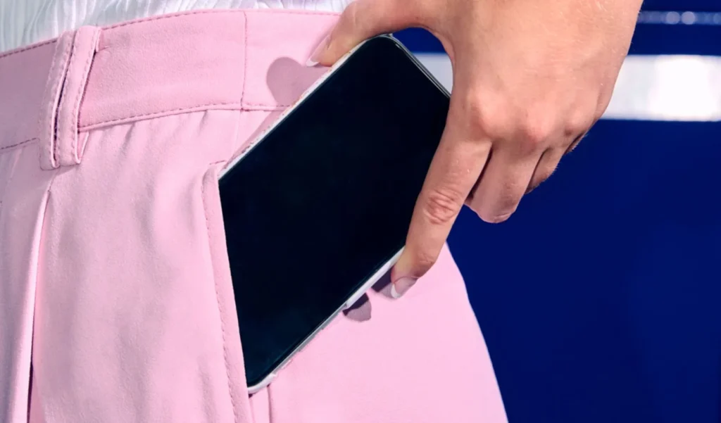 Person placing smartphone into pocket while preparing for work – staff roster guide visual.