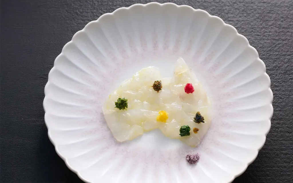 A white plate featuring a dish, garnished and ready to be served.