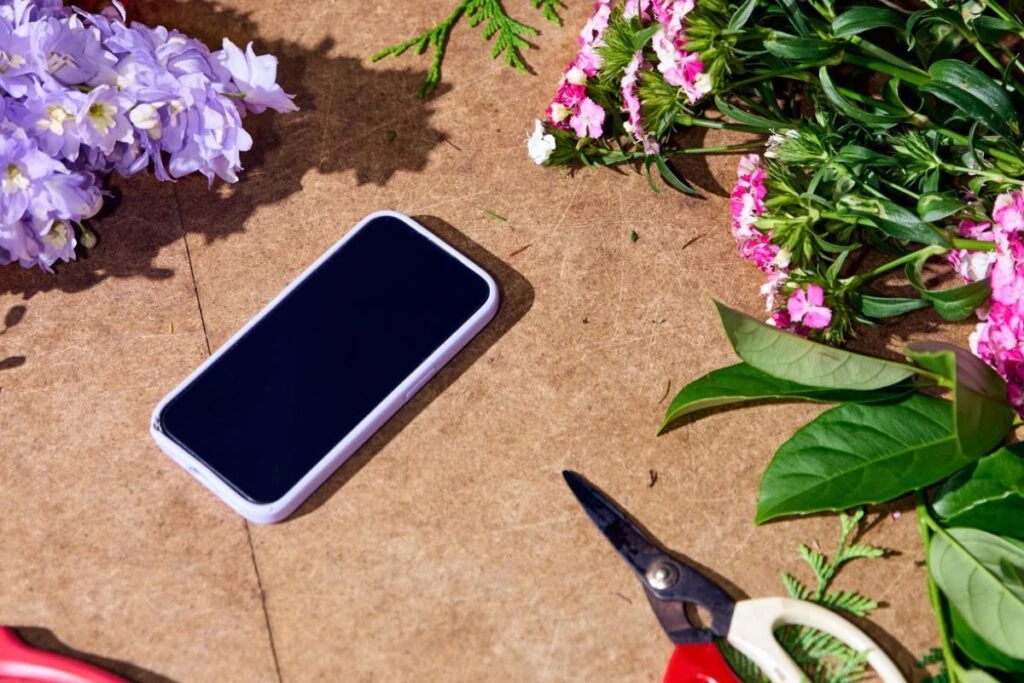 Phone on a surface surrounded by flowers