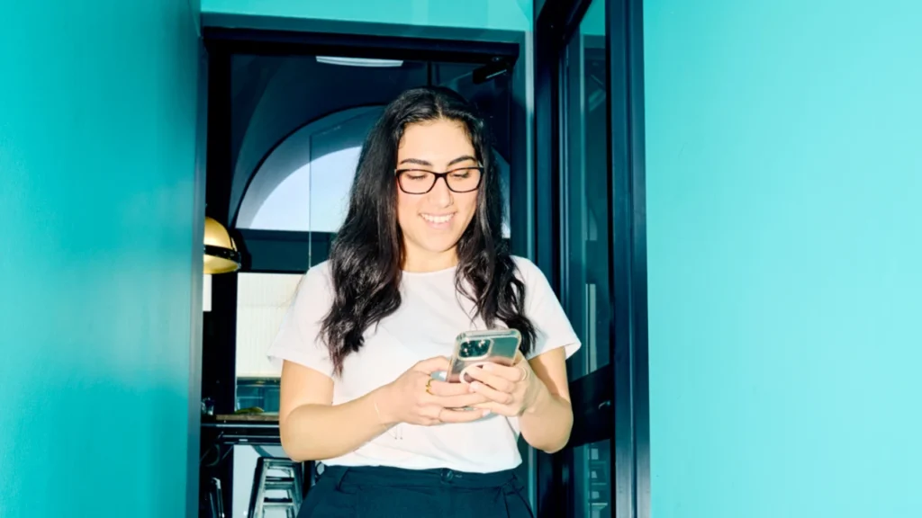 Woman smiling as she uses her phone
