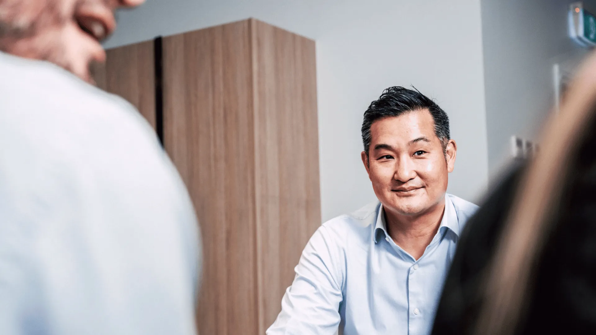 A smiling male manager listening attentively during a meeting, representing a positive and constructive job promotion and performance review conversation with an employee.