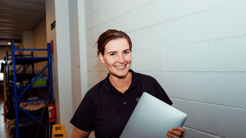 A smiling woman holding up a laptop