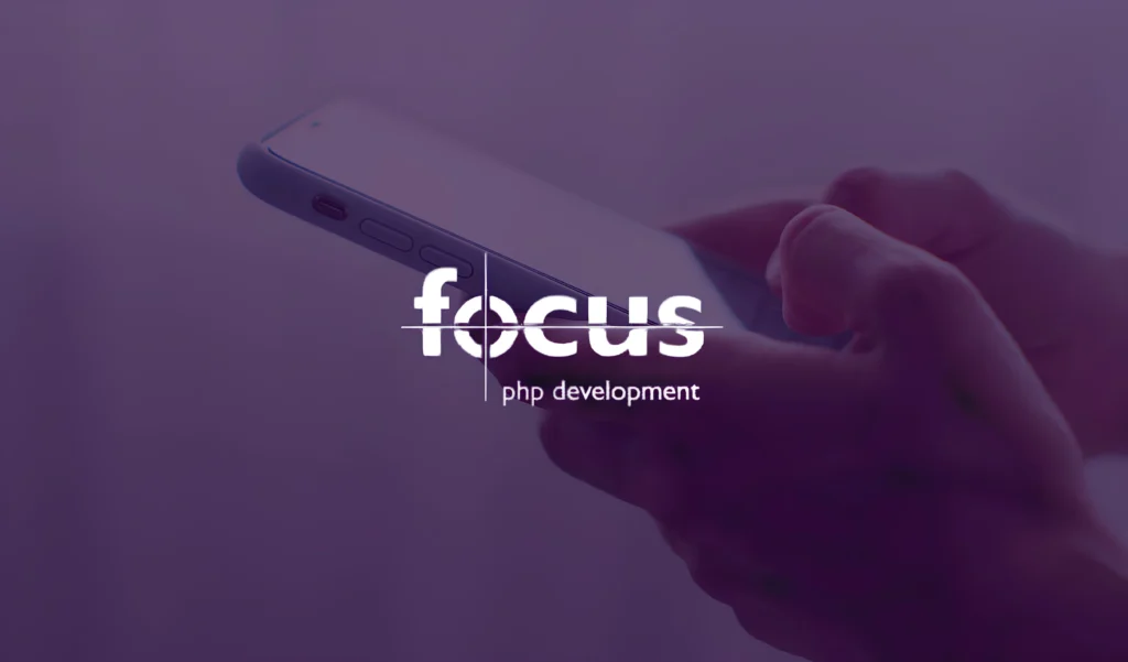 Hands hold a smartphone against a purple background. Overlaid text reads "Focus PHP Development," conveying a professional and modern tone.